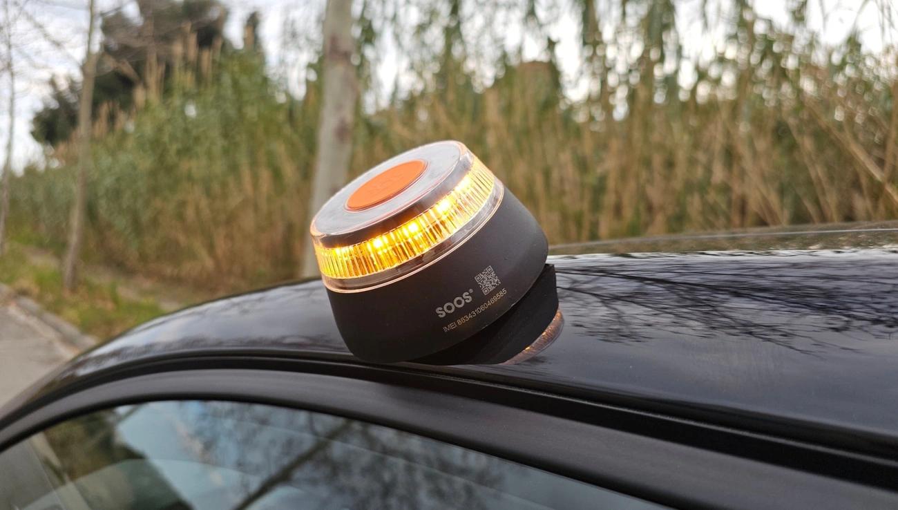 SOOS V16 connected beacon flashing amber light on a car roof for roadside emergency alert.